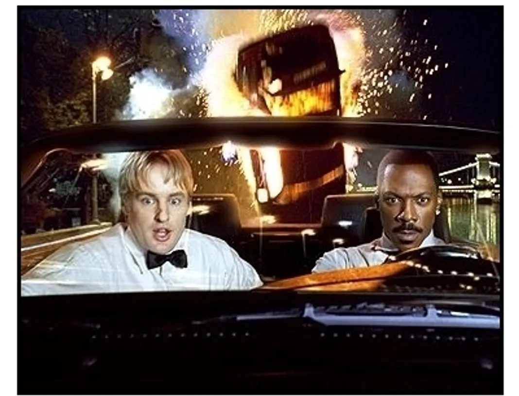 I Spy movie still:Special agent Alex Scott (Owen Wilson) and Kelly Robinson (Eddie Murphy) escape on a car carrier while being pursued by villainous thugs in I Spy